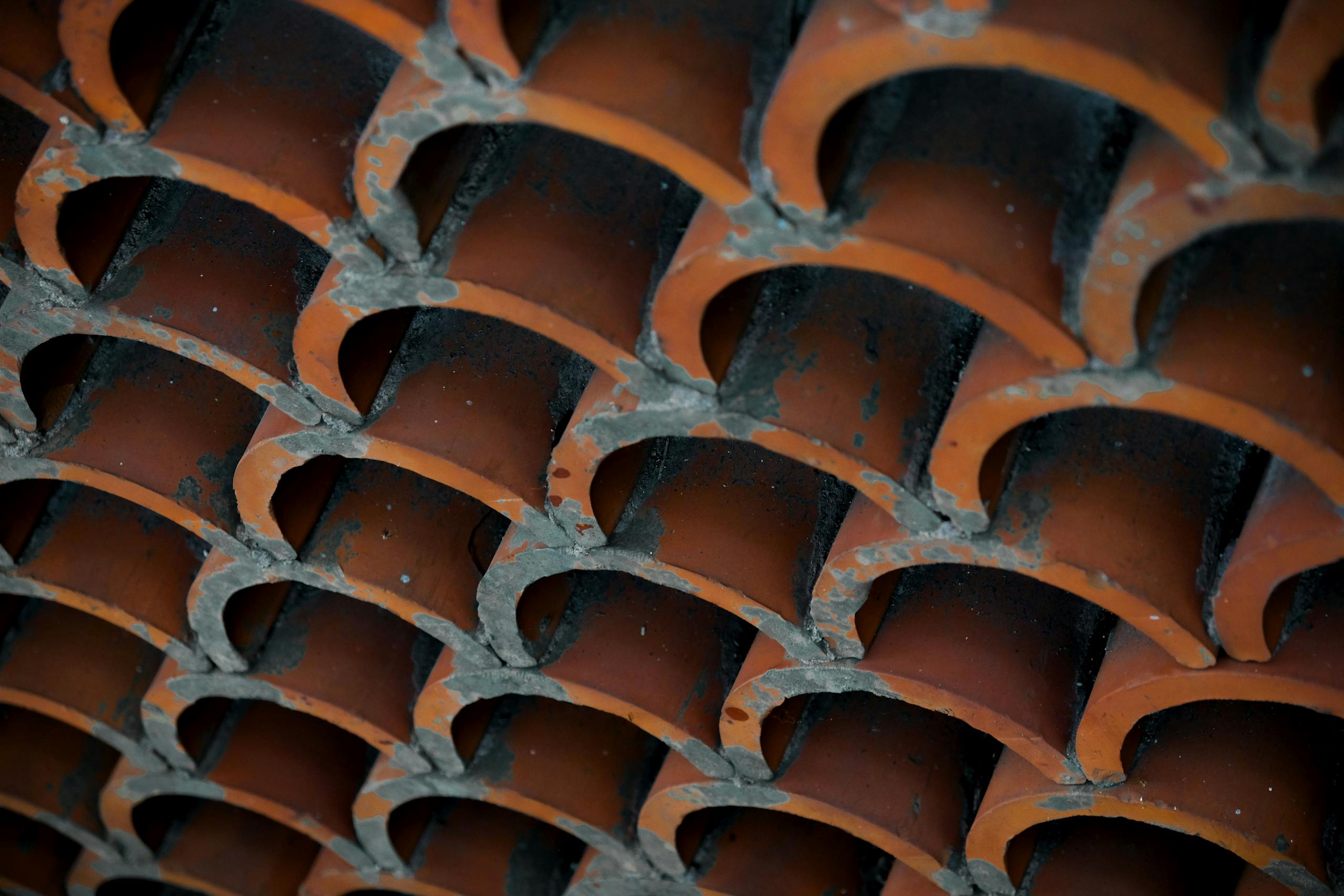 Detailed view of weathered terracotta roof tiles stacked in an overlapping pattern.